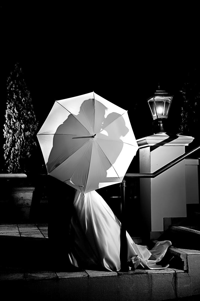 Black and white photo - silhouette of bride and groom kissing behind umbrella - photo by South Africa based wedding photographer